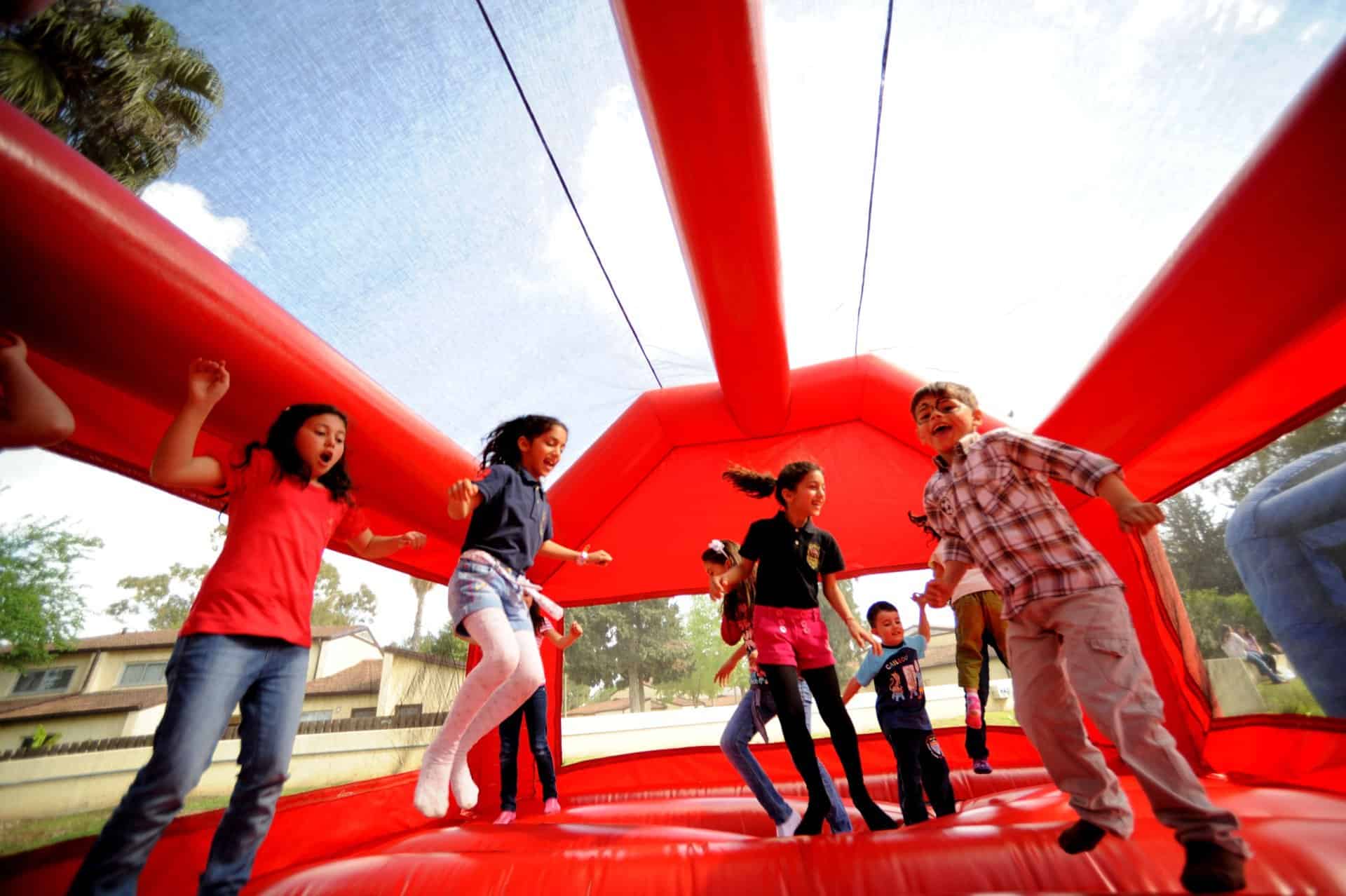 Kids jumping inside a red bouncy castle at a backyard birthday party in Toronto