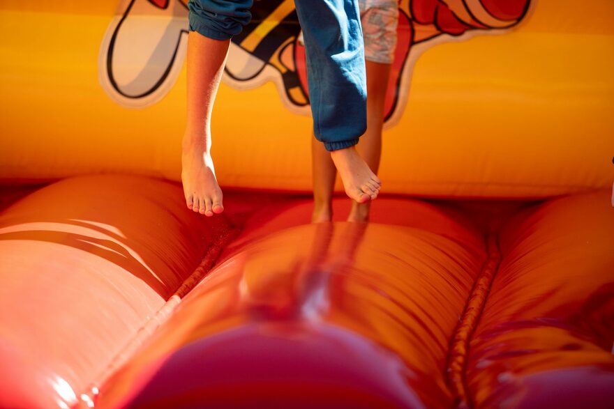 Kids bouncing inside a bright orange bouncy castle