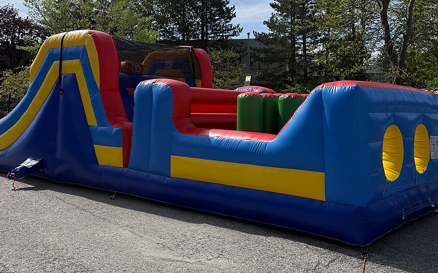 A Jumbo Jumps inflatable obstacle course set up outdoors, with crawl holes, pop-up obstacles and a slide